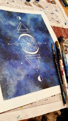 an art project with space and stars in the background, including paintbrushes and watercolors