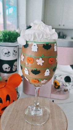 a glass filled with whipped cream sitting on top of a wooden table next to halloween decorations