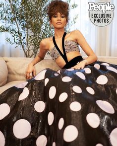 a woman sitting on top of a couch wearing a polka dot skirt and crop top