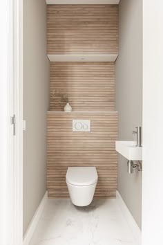 a white toilet sitting inside of a bathroom next to a wall mounted faucet