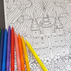 colored pencils and markers next to an adult coloring book with castle in the background