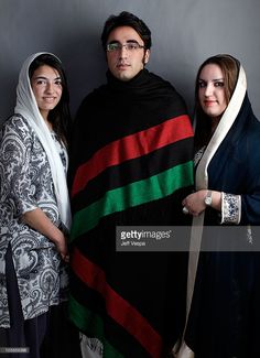 three people standing next to each other in front of a gray wall wearing scarves