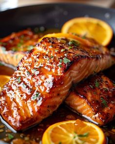 two salmon fillets in a skillet with orange slices