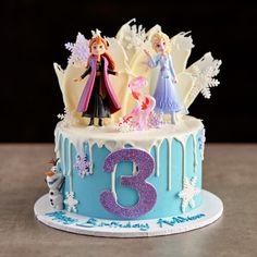 a frozen princess birthday cake with the number three on it and figures in frosting