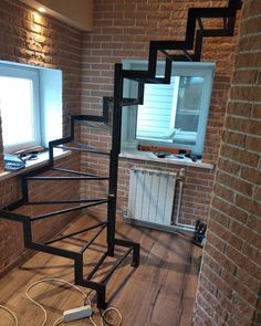 a spiral staircase made out of metal pipes and wires in a room with brick walls