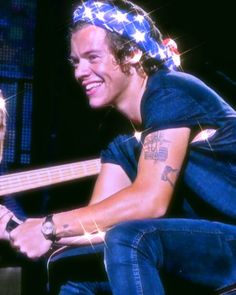 a man with a bandana on his head sitting next to a woman holding a guitar