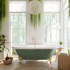 a green bath tub sitting under a window next to a potted plant in a bathroom