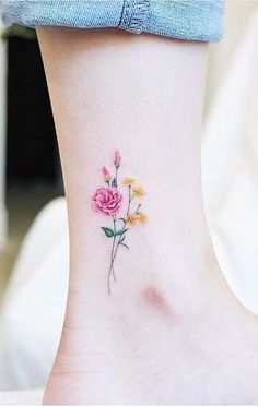 a small flower tattoo on the ankle with yellow and pink flowers in it's center