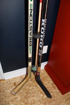 two hockey sticks are next to each other in front of a blue wall and red door