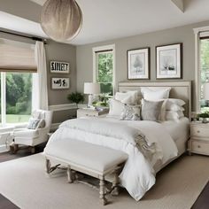 a white bed sitting in a bedroom next to two windows with pictures on the wall