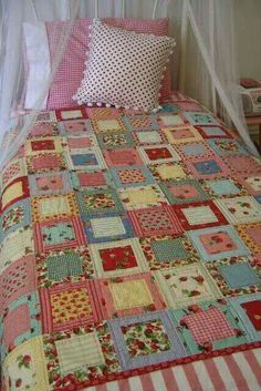 a bed with pink and blue quilts on it