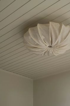 the ceiling is covered in white fabric and has a flower shaped light fixture hanging from it