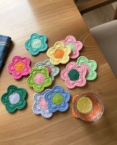 crocheted flowers on a table next to a glass of water and a napkin