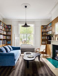 a living room filled with furniture and bookshelves next to a fire place in front of a window