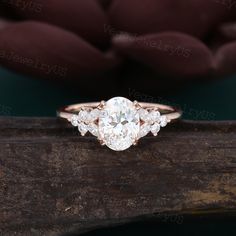 an oval cut diamond ring on top of a piece of wood