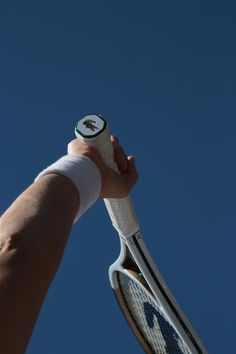 a person holding a tennis racket up in the air with their hand on it