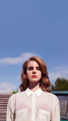 a woman standing in front of a green car wearing a white shirt and black pants