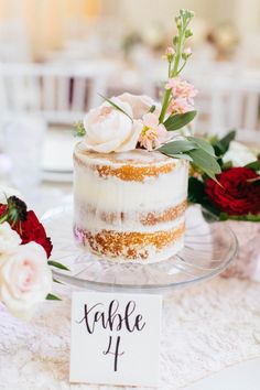 a table topped with a cake covered in frosting next to red and white flowers