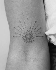 a small sunflower tattoo on the side of a woman's lower back leg