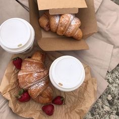 some croissants and strawberries are on the table next to starbucks cups