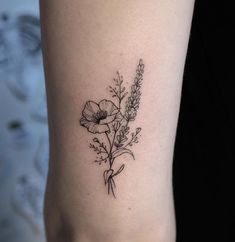 a small flower tattoo on the right side of the leg, with leaves and flowers around it