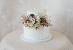 a close up of a cake on a table with white frosting and floral decorations