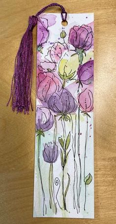 a bookmark with flowers painted on it and tassels hanging from the side