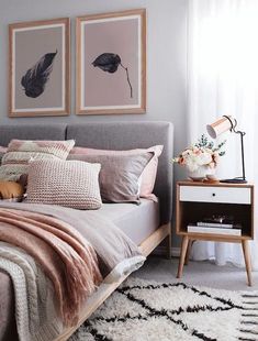 a bedroom with pink and grey bedding, two pictures on the wall above it