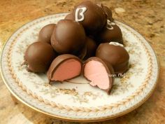 a plate that has some chocolates on it with pink and white frosting in the middle