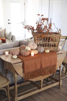 a table topped with candles and pumpkins on top of a wooden table next to a couch