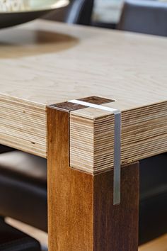 a close up of a wooden table with chairs in the background