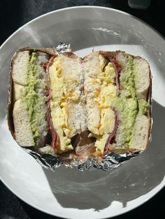 the sandwich is cut in half and sitting on top of a white plate with silver foil