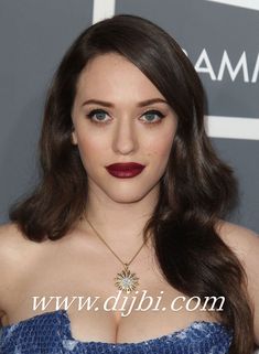 a woman with long brown hair wearing a blue strapless dress and red lipstick at an awards event