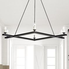 a black chandelier hanging from the ceiling in a living room with white walls