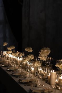 a long table is set with candles and flowers in vases, plates and glasses