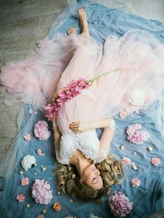 a woman laying on top of a bed covered in flowers