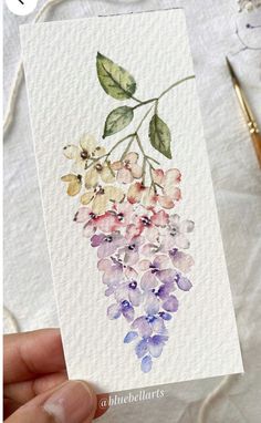 a hand holding up a card with watercolor flowers on it