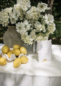 a vase filled with white flowers next to lemons