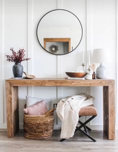 a wooden table with a mirror on the wall above it and a basket next to it