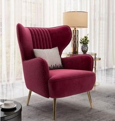 a living room with a red chair and lamp on the side table in front of a window