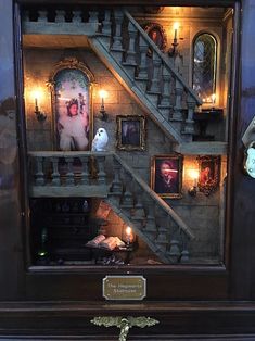 a dollhouse with stairs and pictures on the wall in it's display case