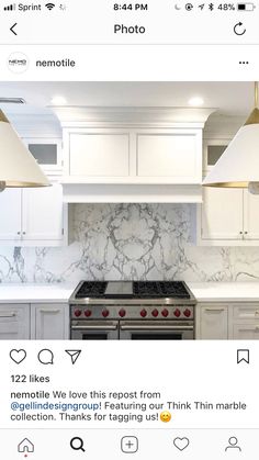 an instagramted photo of a kitchen with white cabinets and marble counter tops, two pendant lights over the stove