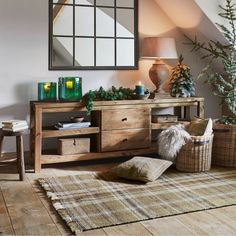 a living room filled with furniture next to a christmas tree and potted plant on top of a wooden table