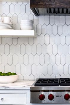 a stove top oven sitting inside of a kitchen next to a bowl of green apples