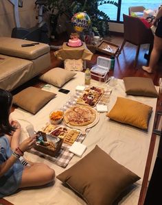 a woman sitting on the floor in front of a table full of food