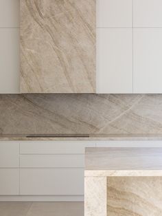 an empty kitchen with marble counter tops and white cupboards in the backround