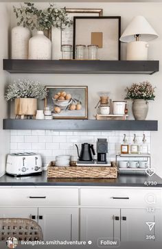 a kitchen with white cabinets and black counter tops, open shelving above the stove