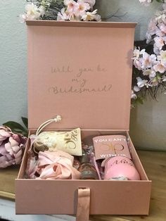 a pink box filled with personal care items on top of a wooden table next to flowers