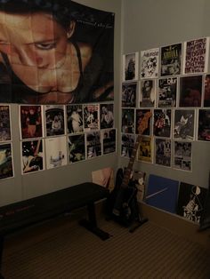 a guitar sitting in front of a wall covered with pictures and posters on it's sides