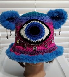 a crocheted hat with an eyeball and chains hanging from the brim